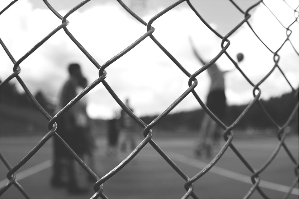 young people playing basketball behind a fence